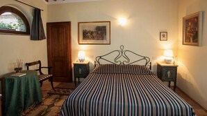 A bedroom with a bed, two bedside tables with lamps, a wooden door, a framed picture on the wall, and a window with curtains. - Beautiful accommodation in a quiet location and with a huge garden,Wi-Fi,t5 (Pomaia)