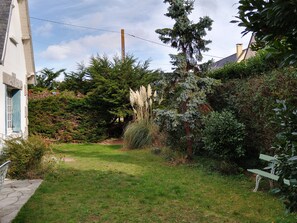 Stroll through the serene garden, featuring a well-manicured lawn, lush shrubs, and a winding pathway.