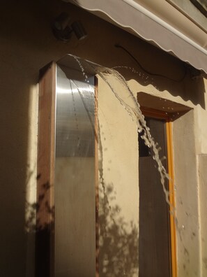 A close-up of a wall with a water leak, a metal door frame, and a wooden door.