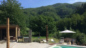 Area piscina con lettini e una zona relax coperta.