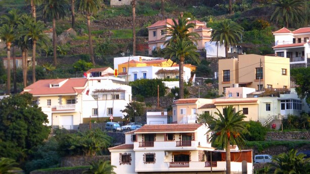 A residential area with houses, palm trees, and a hillside. - Small house in a village, with a front yard, set back from the main street, with Wi-Fi (Valle Gran Rey)