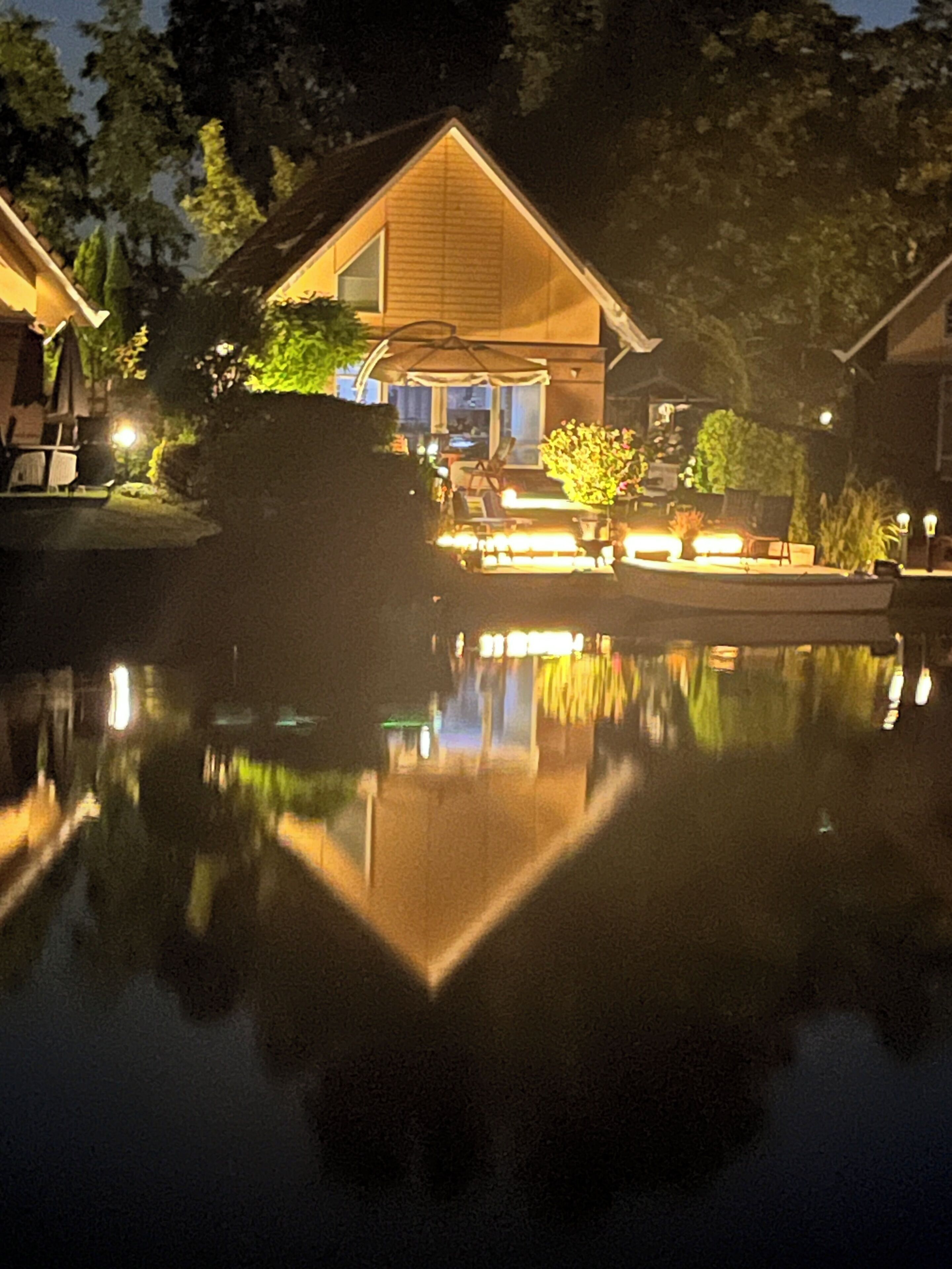 A house with a visible deck area, a swimming pool, and a well-lit outdoor space.