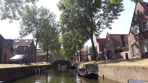 Ein Kanal mit einem Boot, einer Brücke und traditionellen Gebäuden am Wasserufer.