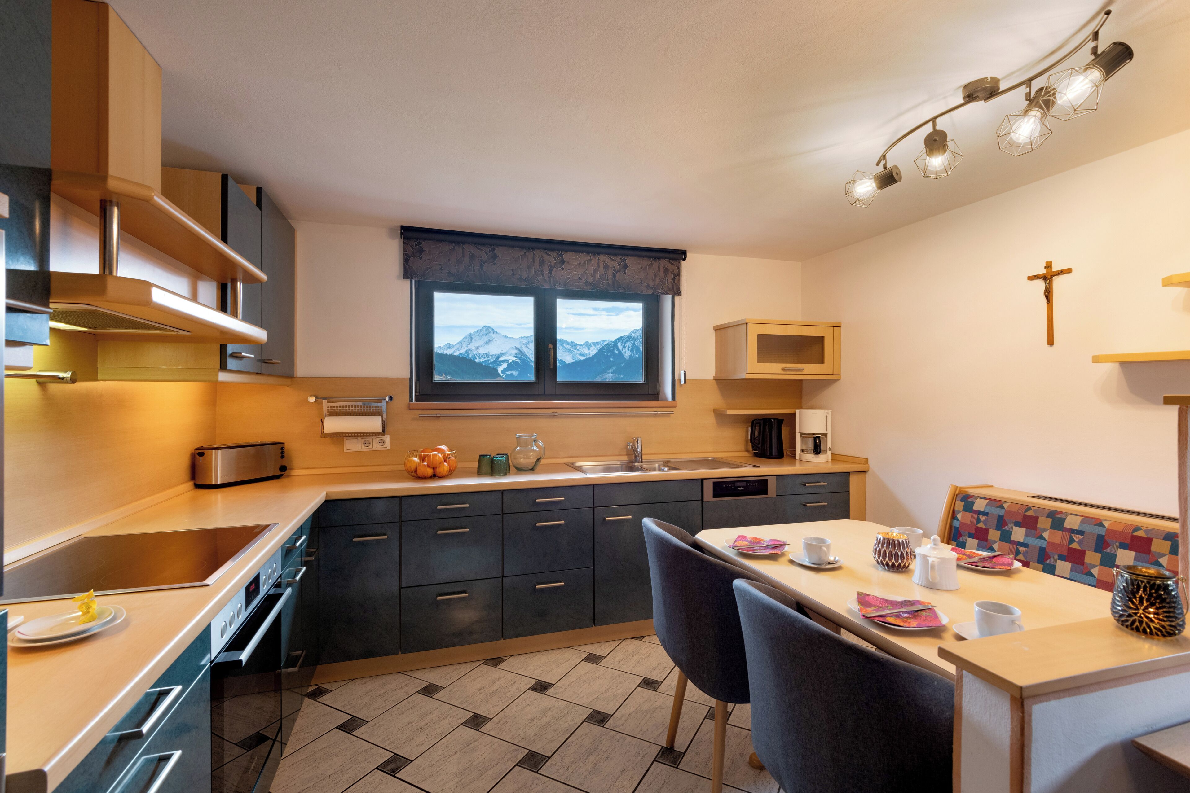 Une cuisine moderne dotée d’une grande fenêtre, d’appareils électroménagers intégrés et d’un coin repas offrant une vue sur les montagnes.