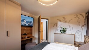Ein modernes Schlafzimmer mit einem Bett, einem Fernseher, einem Holztisch und einer Wand mit floralen Mustern.