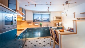 Eine moderne Küche mit Backofen, einem Fenster mit Blick auf die Berge und einem Essbereich mit Tisch und Stühlen.