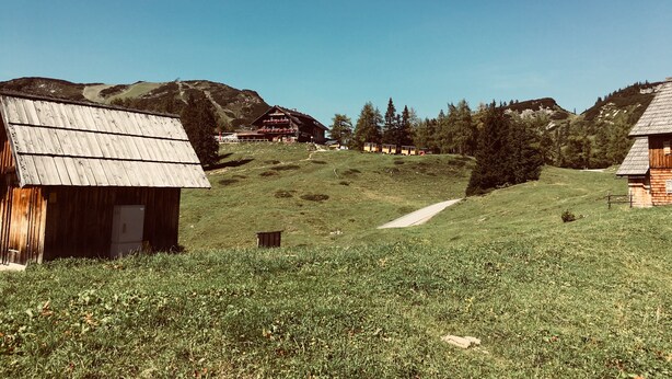 Landligt område med træhuse, klar himmel og et bakket landskab.