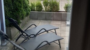 A patio with two lounge chairs, a view of a river, and a distant building with a crane. - Modern, premium lake view vacation apartment over 2 floors (Waldeck -Scheid)