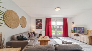 A modern living room with a sofa, a coffee table, a TV, and a wooden cabinet. - Awesome home in Wemeldinge with kitchen (Wemeldinge)