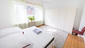 A bedroom with a bed, a window with curtains, a radiator, a plant, and a wardrobe. - Apartment Hörster in the center of Detmold (Detmold)