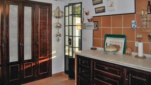 A kitchen with wooden cabinets, a tiled backsplash, and various kitchen items on the counter.