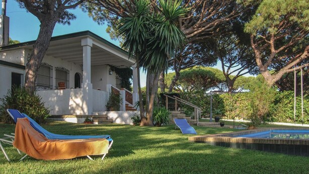 A house with a covered porch, a swimming pool, and two lounge chairs.