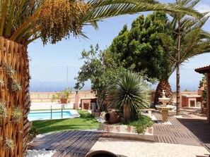 A courtyard with a pool, palm trees, and a view of the sea. - Romantic, historic country house with tropical garden (Arico)
