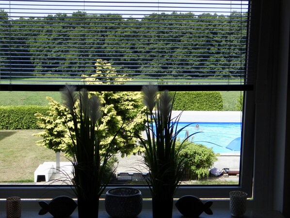 A window with a view of a swimming pool, a lawn, and a hedge. - Beach nest in Scharbeutz / Haffkrug, 20 meters to the Baltic Sea beach (Haffkrug)