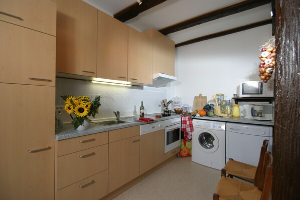 A kitchen with wooden cabinets, a microwave, a washing machine, and a sink.
