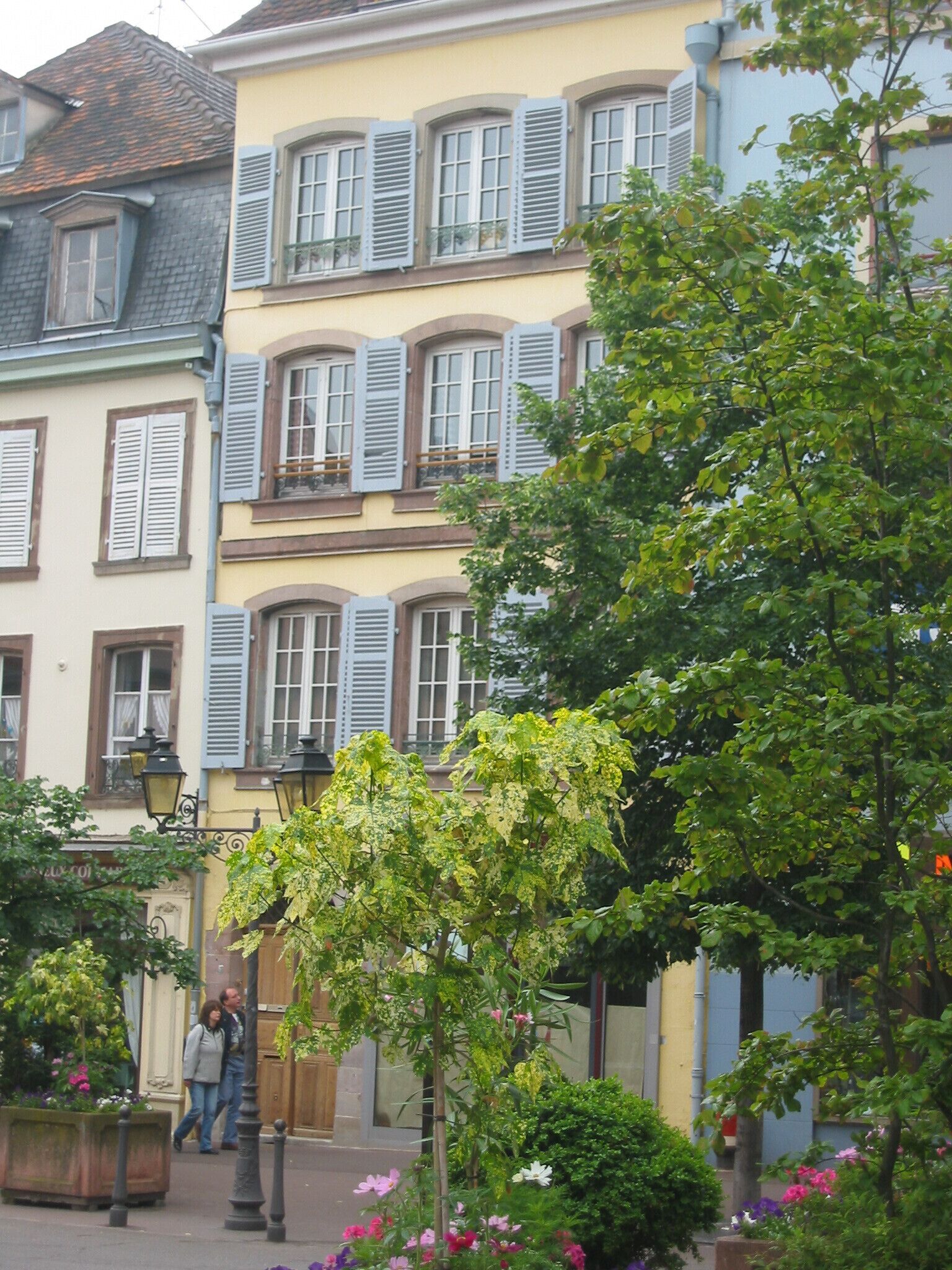 A street with buildings featuring traditional architecture, including shuttered windows and balconies.
