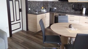 Een compacte keuken met een ingebouwde vaatwasser, een magnetron en een klein aanrecht. Er is een eettafel met vier stoelen.