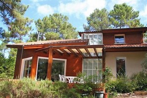 Une maison à deux étages avec une façade en bois, un patio couvert et un jardin.