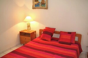 A bed with a striped blanket, a bedside lamp, and a nightstand with a lamp. - Beautiful house with idyllic views G0268 (Lacanau)