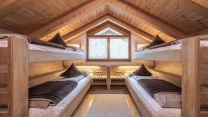 Une chambre mansardée chaleureuse avec deux lits superposés, un puits de lumière et une fenêtre.