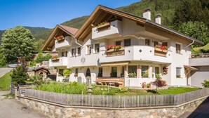 Un chalet à deux étages doté de balcons, d’un mur en pierre et d’une clôture en bois.