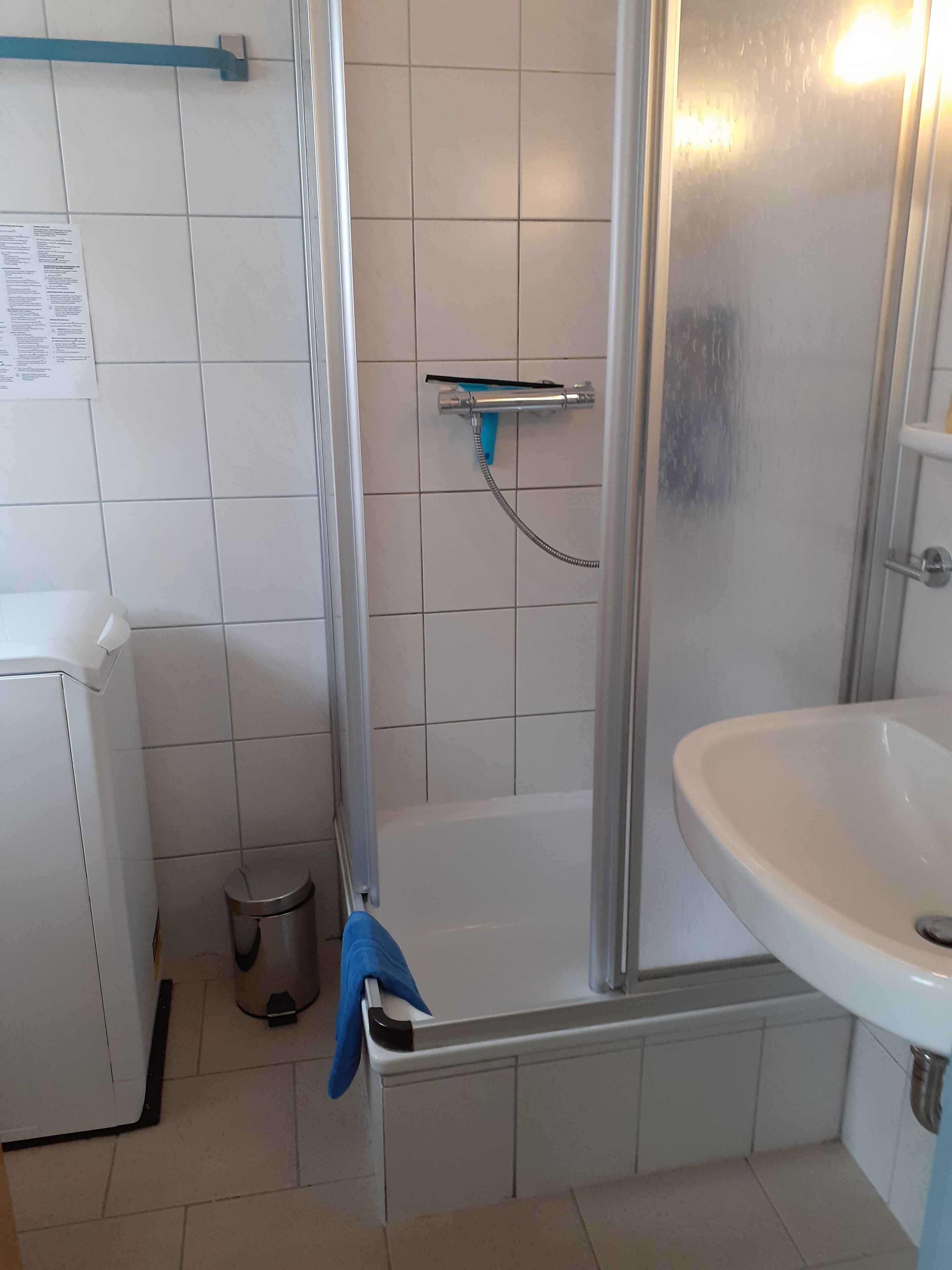 Ein Badezimmer mit Dusche, Waschbecken und Mülleimer.