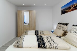 A bedroom with a bed, a wardrobe, and a cityscape view.