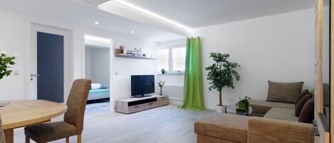 Uma sala de estar moderna com uma mesa de jantar, sofá e televisão.