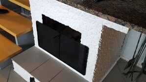 Una cocina con pared blanca texturizada, encimera negra y chimenea empotrada.