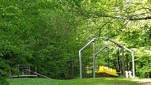 Un parque infantil con un tobogán amarillo y una estructura para escalar.