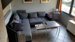 Una sala de estar moderna con un sofá modular, una mesita de centro y dos cuadros en la pared.