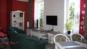A living room with a TV, a bookshelf, and two green sofas. - cozy, quiet apartment near Spreewald, central location, pets welcome (Neupetershain)