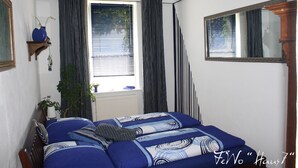 A bedroom with a bed, a window with curtains, a mirror, and a plant. - cozy, quiet apartment near Spreewald, central location, pets welcome (Neupetershain)