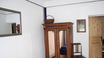 Ein Schlafzimmer mit einem Bett, einem Holzschrank, einem Stuhl, einem Spiegel und einer Tür.