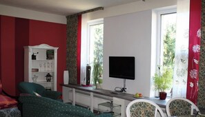 A living room with a TV, a bookshelf, and two green sofas.