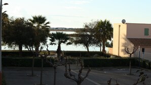 A parking area with trees and a building in the background. - Very nice vacation home, top location, only 50 m to the beach, close to the harbor. 6 persons (Gruissan)