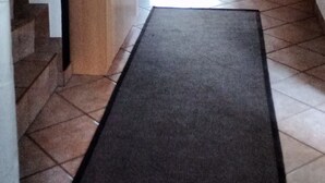 Een gang met vloerkleed, trap, houten kast en een deur naar een andere kamer.