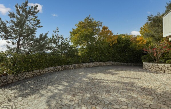 A paved courtyard with stone walls and trees. - Beautiful home in Krk (Krk)