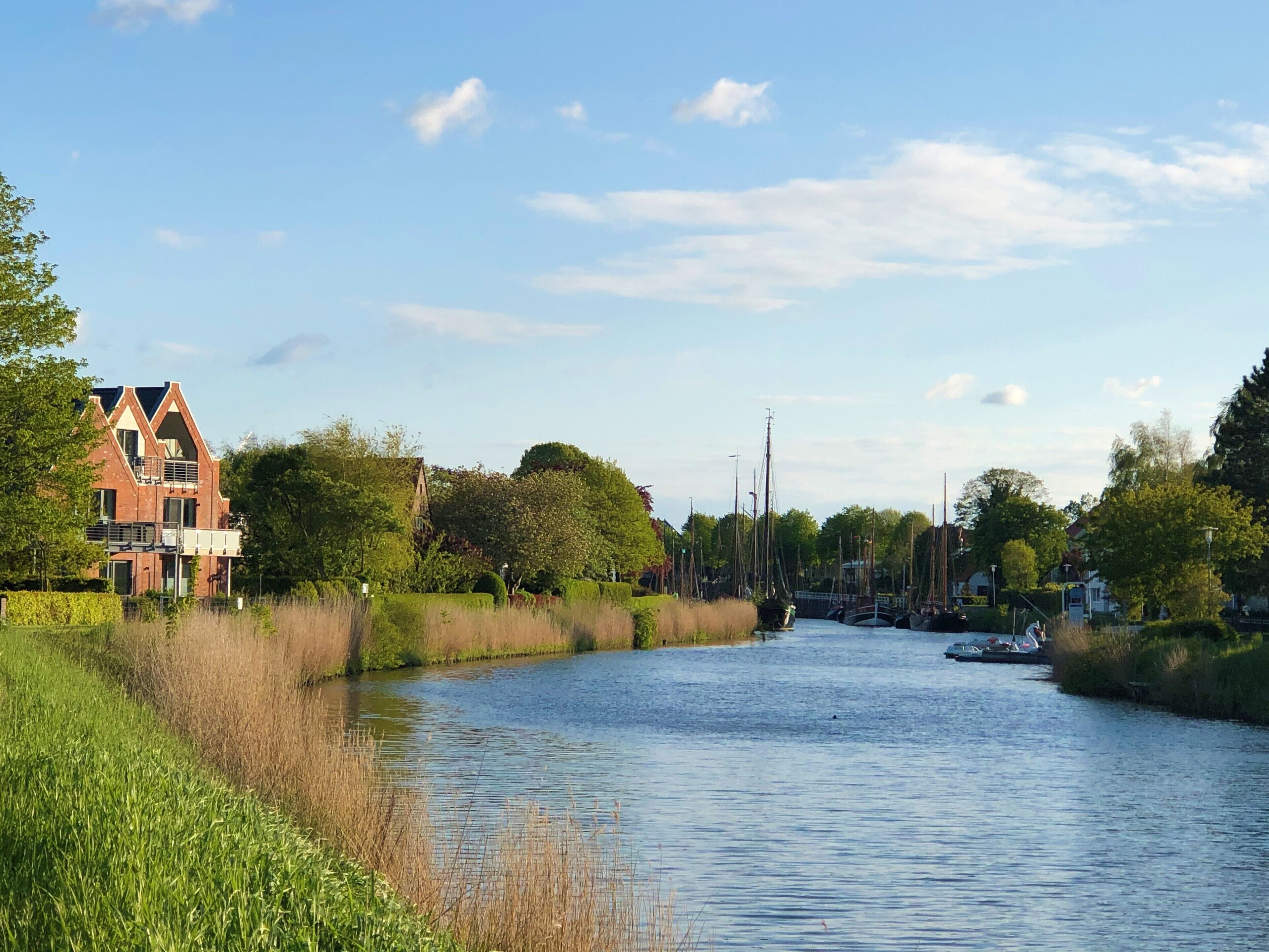 Ein Kanal mit Booten, einer Brücke und einem Gebäude mit einer markanten Dachlinie.
