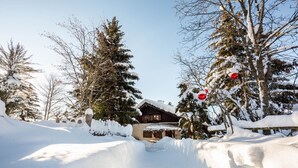 A snow-covered landscape with a wooden cabin and trees.