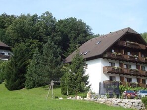 A chalet-style building with a sloped roof, wooden balconies, and a stone foundation.