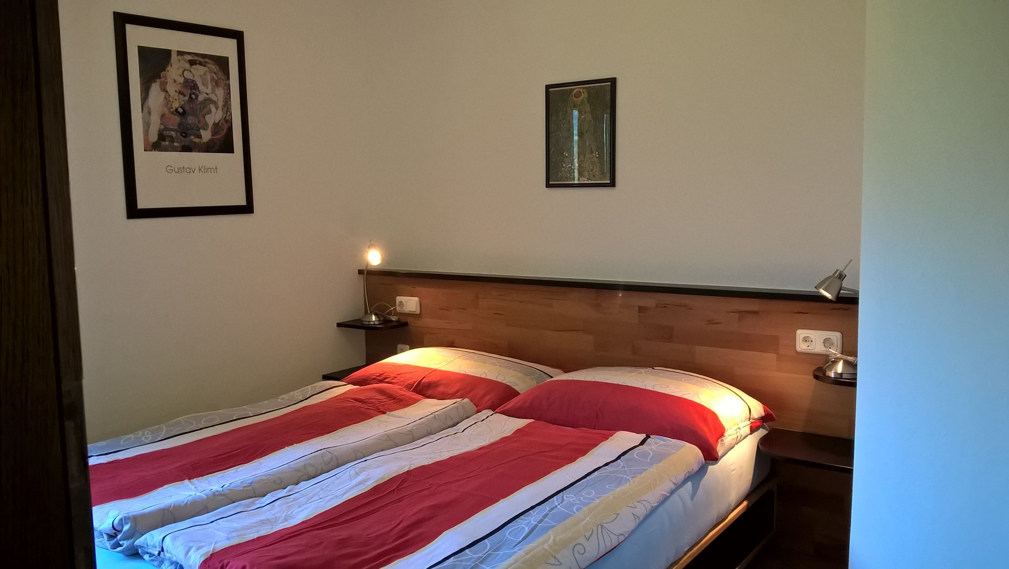 A bed with a striped bedspread, a nightstand with a lamp, and two framed pictures on the wall.