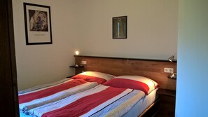 A bed with a striped bedspread, a nightstand with a lamp, and two framed pictures on the wall.