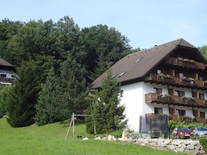 A chalet-style building with a sloped roof, wooden balconies, and a stone foundation.