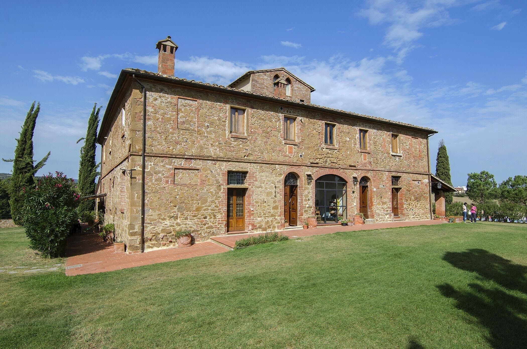 A stone building with a central entrance, arched windows, and a chimney.