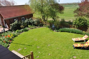 A backyard with a lawn, a windmill, and two lounge chairs.