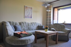 A living room with a sectional sofa, a small table, and a window with curtains.