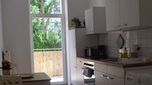 A kitchen with a dining area, a washing machine, and a view through a sliding door. - Apartment, close to the center and in a quiet location on the floodplain forest (Leipzig)