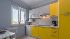 Eine Küche mit einem weißen Tisch, einer Mikrowelle, einer Kaffeemaschine und gelben Schränken.