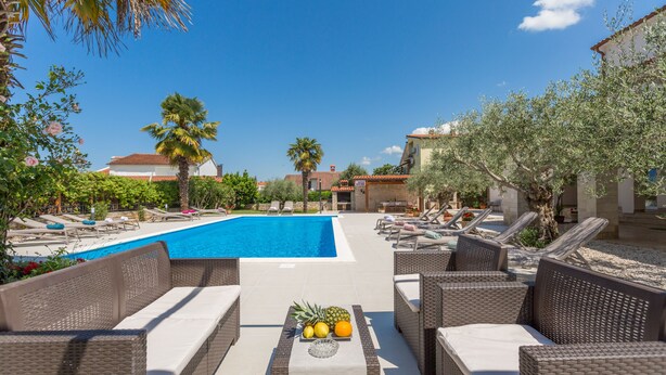 Ein Poolbereich mit Liegestühlen, einem Pool und einem Tisch mit Früchten.